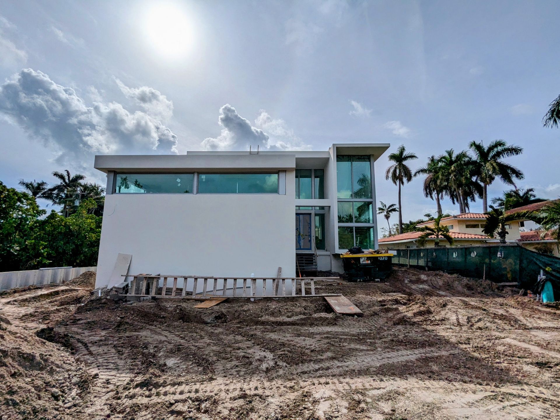 A large white house is being built in the middle of a dirt field.