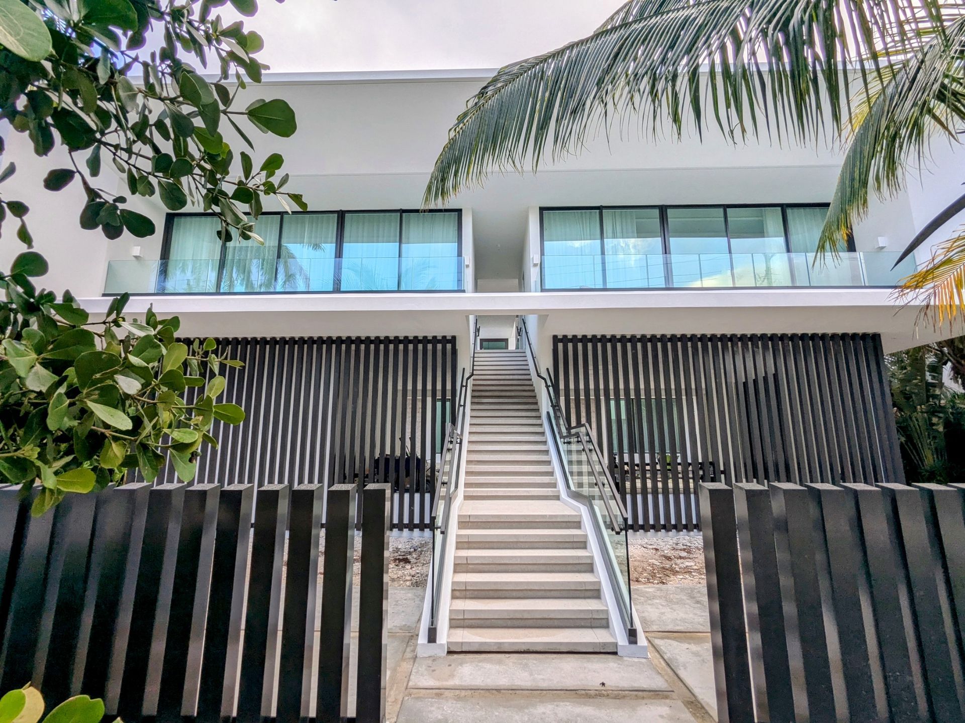The front of a modern house with stairs leading up to it.