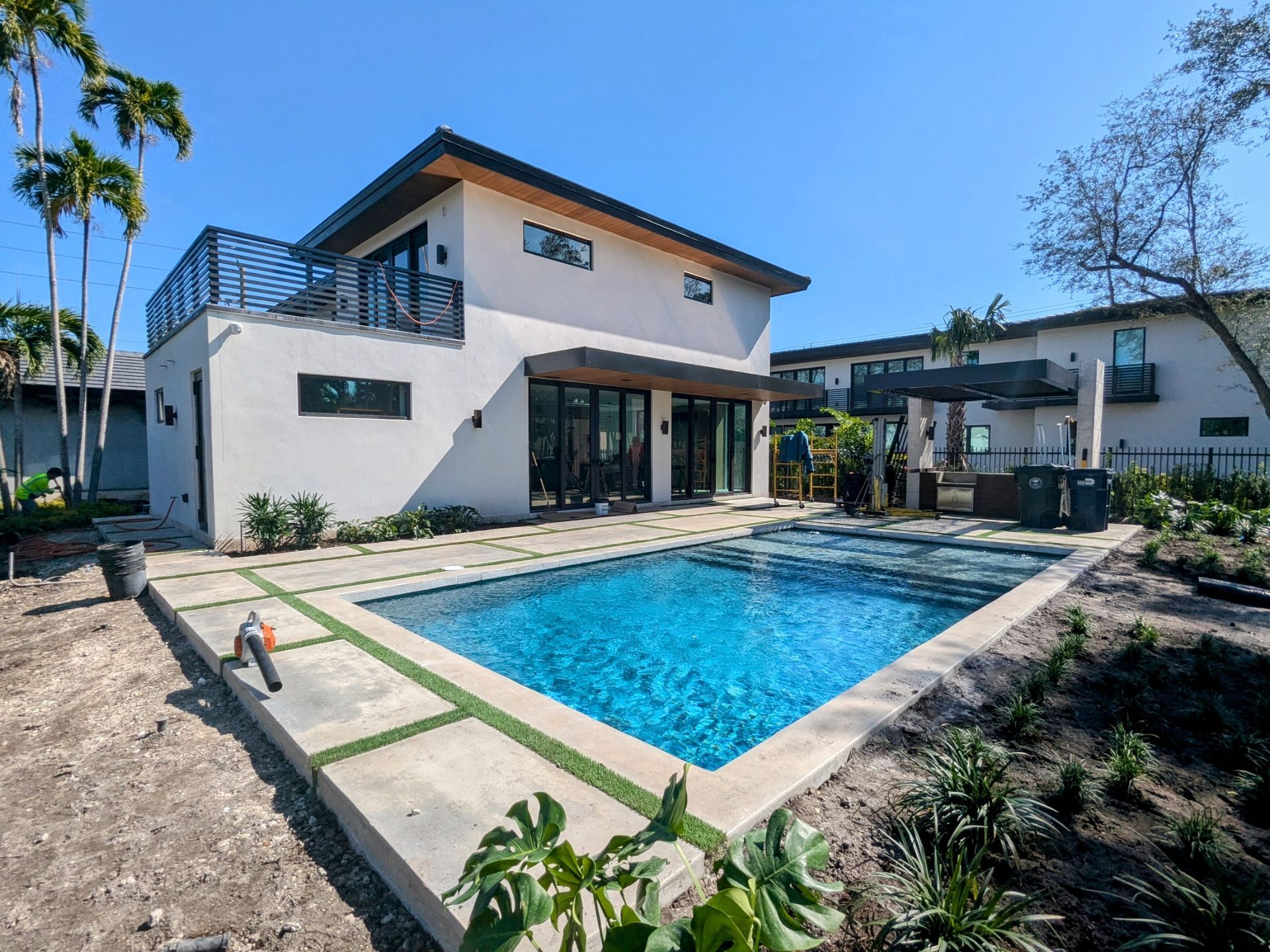 Modern two-story house with a pool in a sunny outdoor setting.