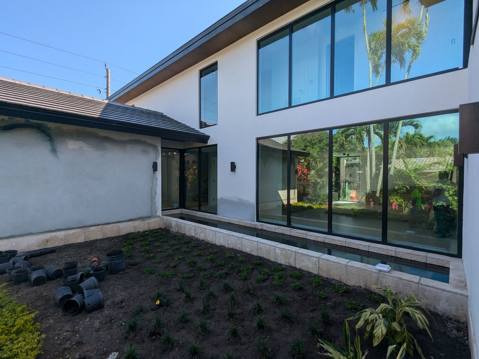 Modern white house with large windows, landscaping, and a blue sky.