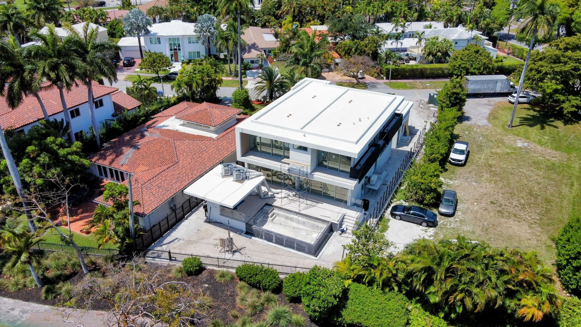 An aerial view of a large house in a residential area surrounded by trees.