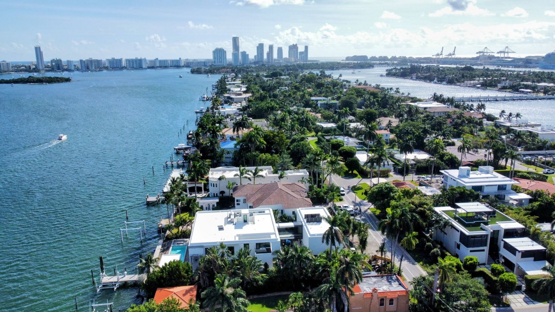 An aerial view of a residential area next to a body of water with a city in the background.