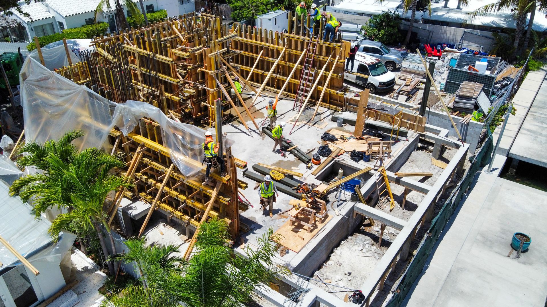 Construction site with wooden framework, workers, and building materials.