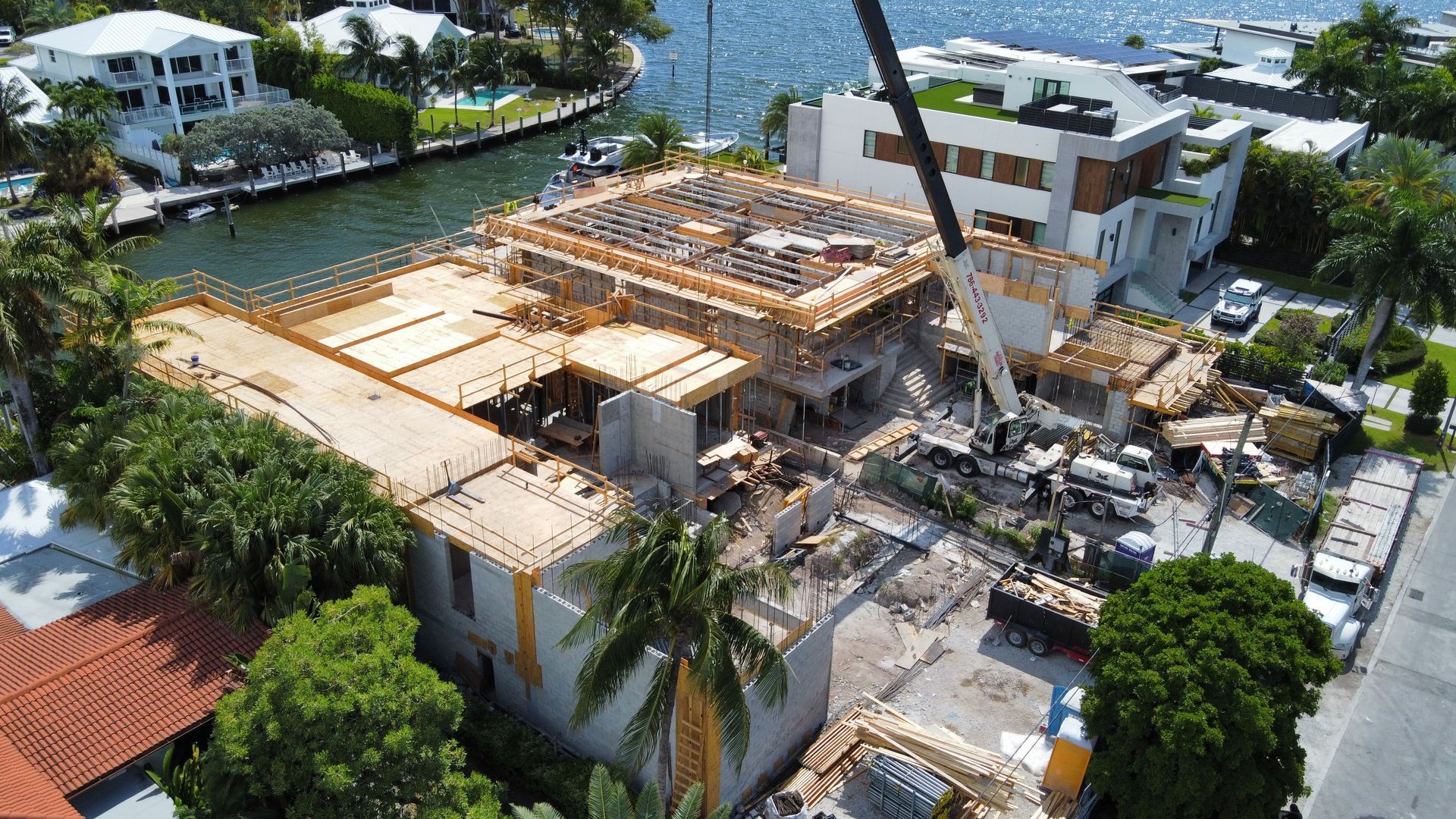Construction site of a house with a crane lifting debris near a waterway.