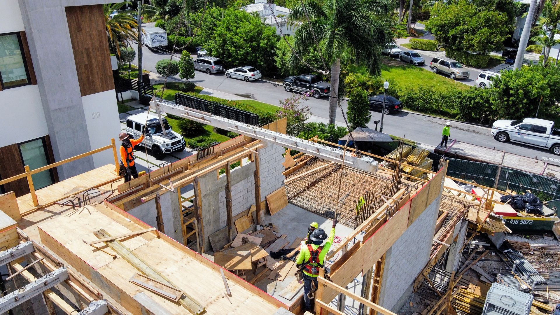 Construction workers building a structure, using lumber. Sunlight. City street in the background.