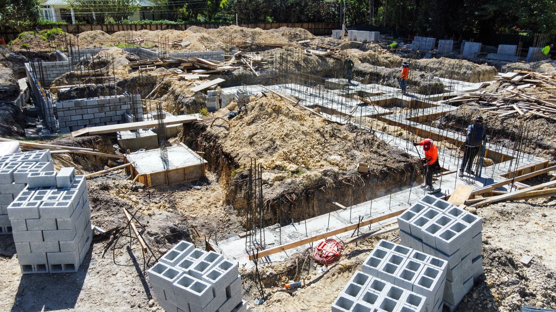 Construction site with foundation work. Workers, rebar, concrete, and cinder blocks.
