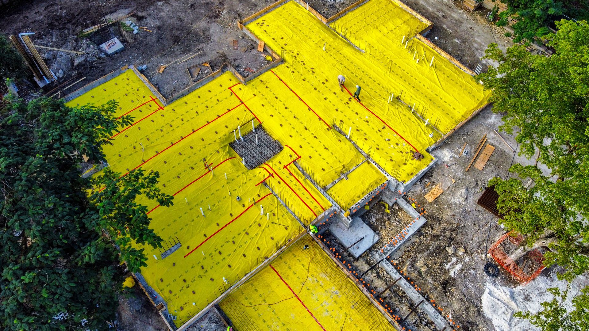 Aerial view of a construction site with yellow insulation covering foundation sections.