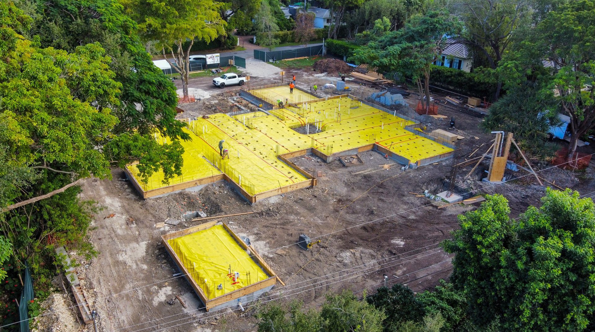 Aerial view of a construction site with yellow foundation forms and a few workers.