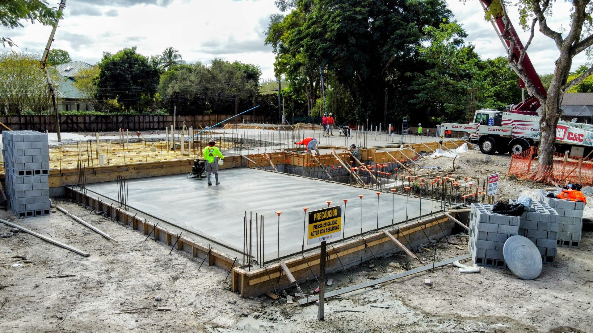 Construction site with a concrete foundation, workers, and a truck.