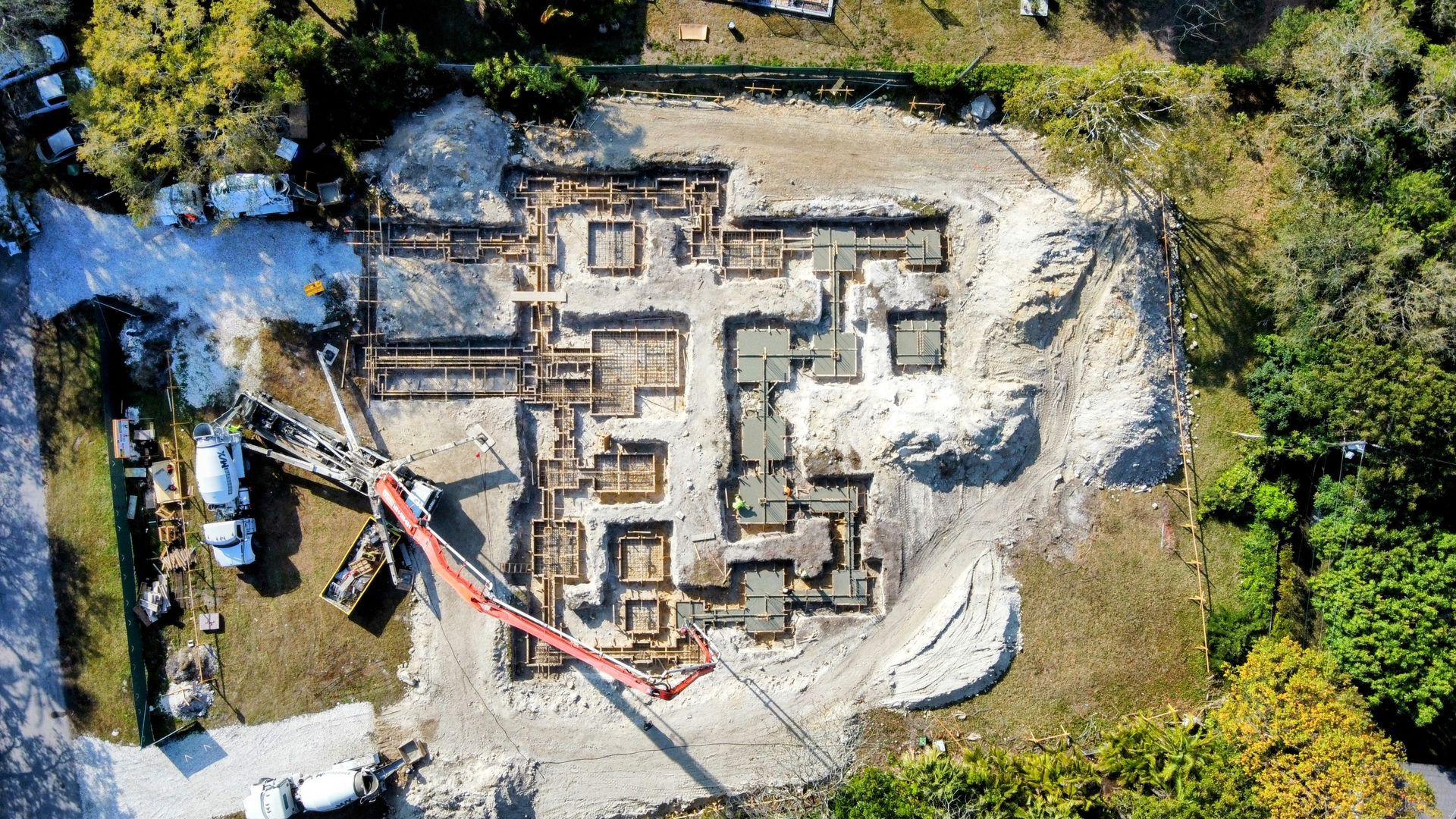 Aerial view of a construction site with foundation forms, machinery, and concrete work in progress.