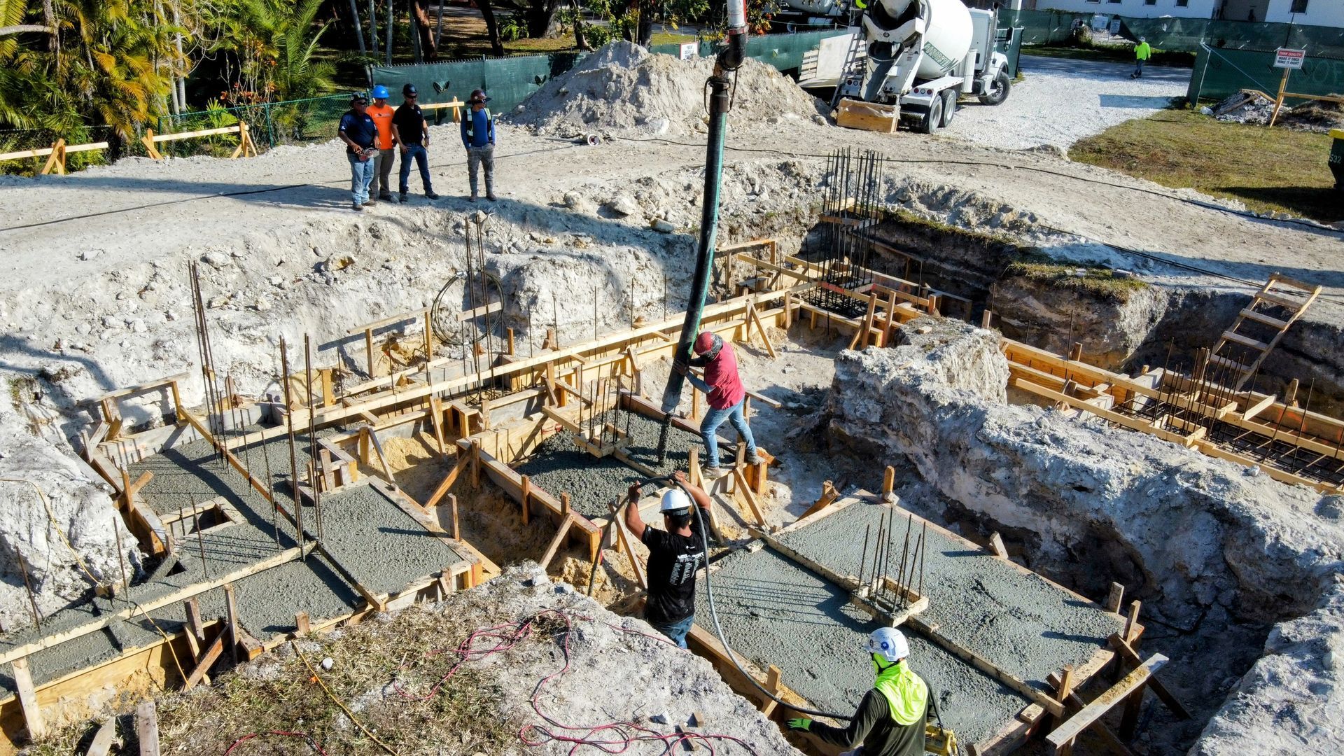 Construction workers pouring concrete into a foundation form with a pump truck.