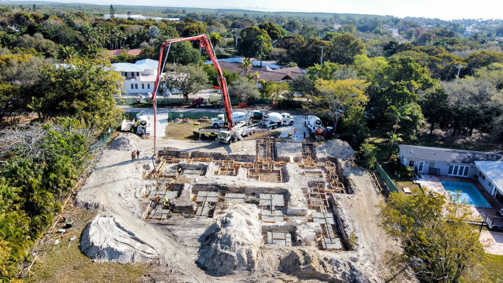 Construction site with concrete pump truck pouring concrete into a foundation.