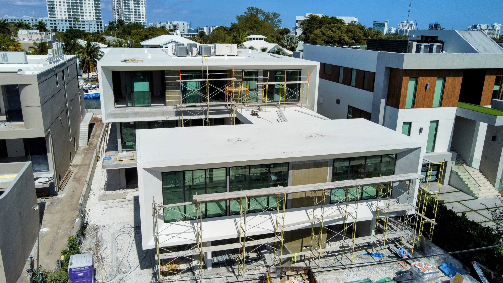Modern multi-story house under construction with glass windows and scaffolding.