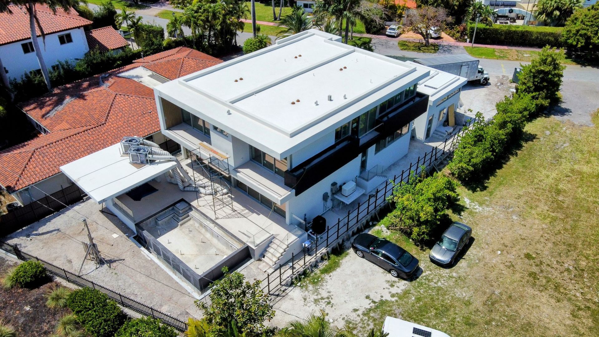 An aerial view of a large white house with cars parked in front of it.