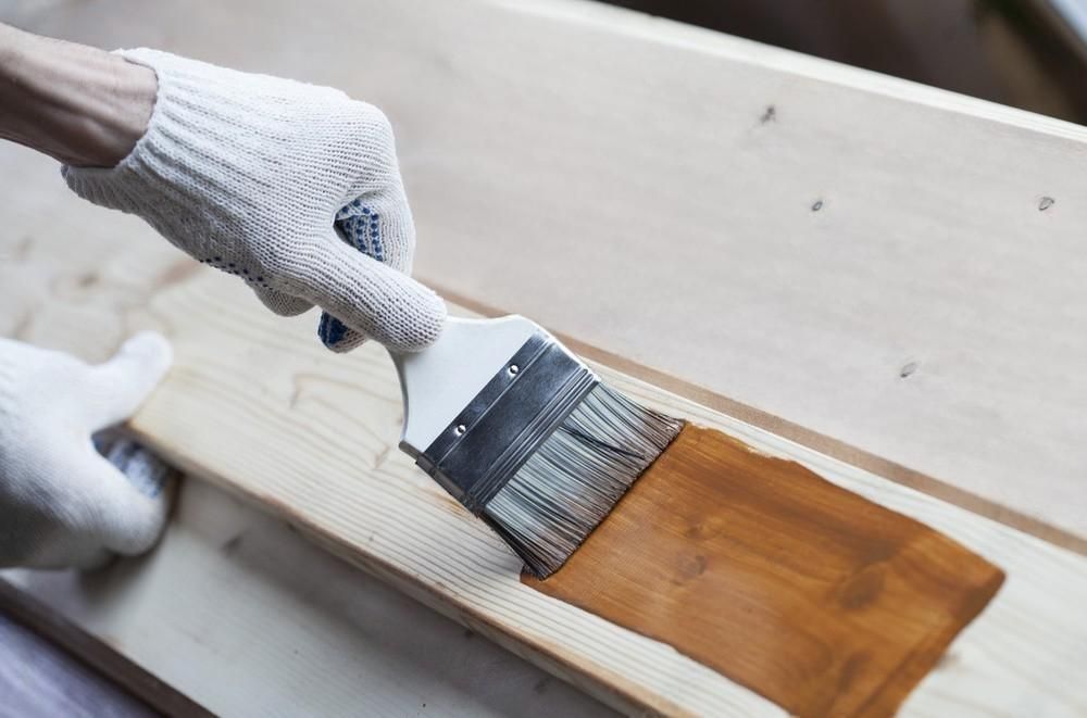 A person is painting a piece of wood with a brush.