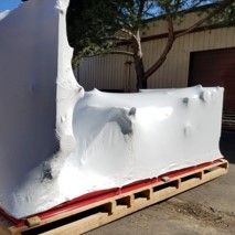 A large object wrapped in plastic is sitting on a wooden pallet.