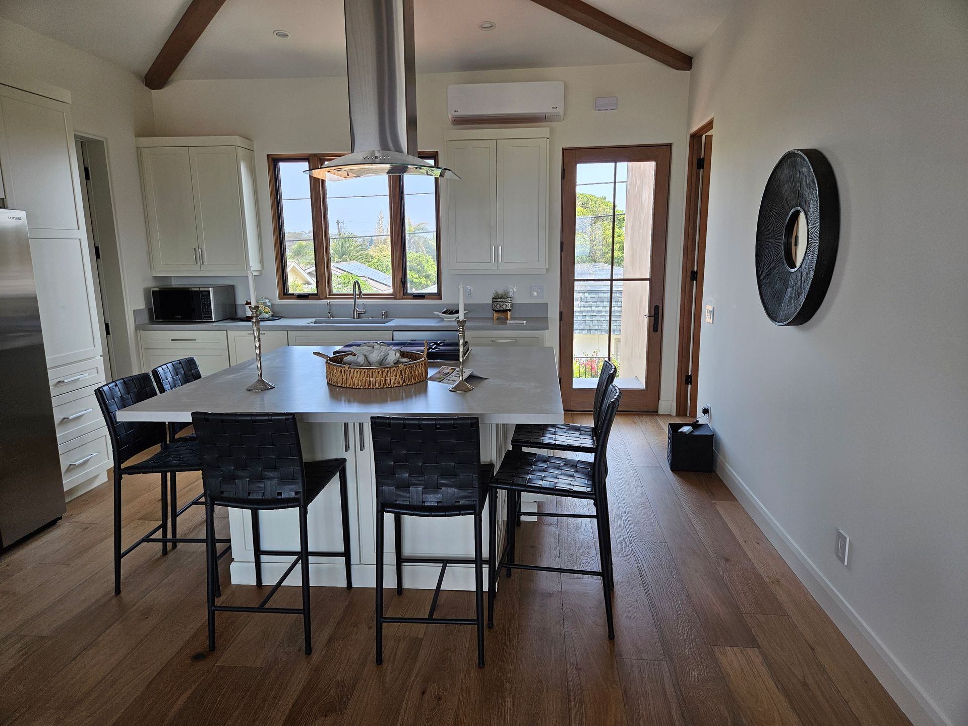 Kitchen with island seating, white cabinets, stainless steel appliances, and wood floor.