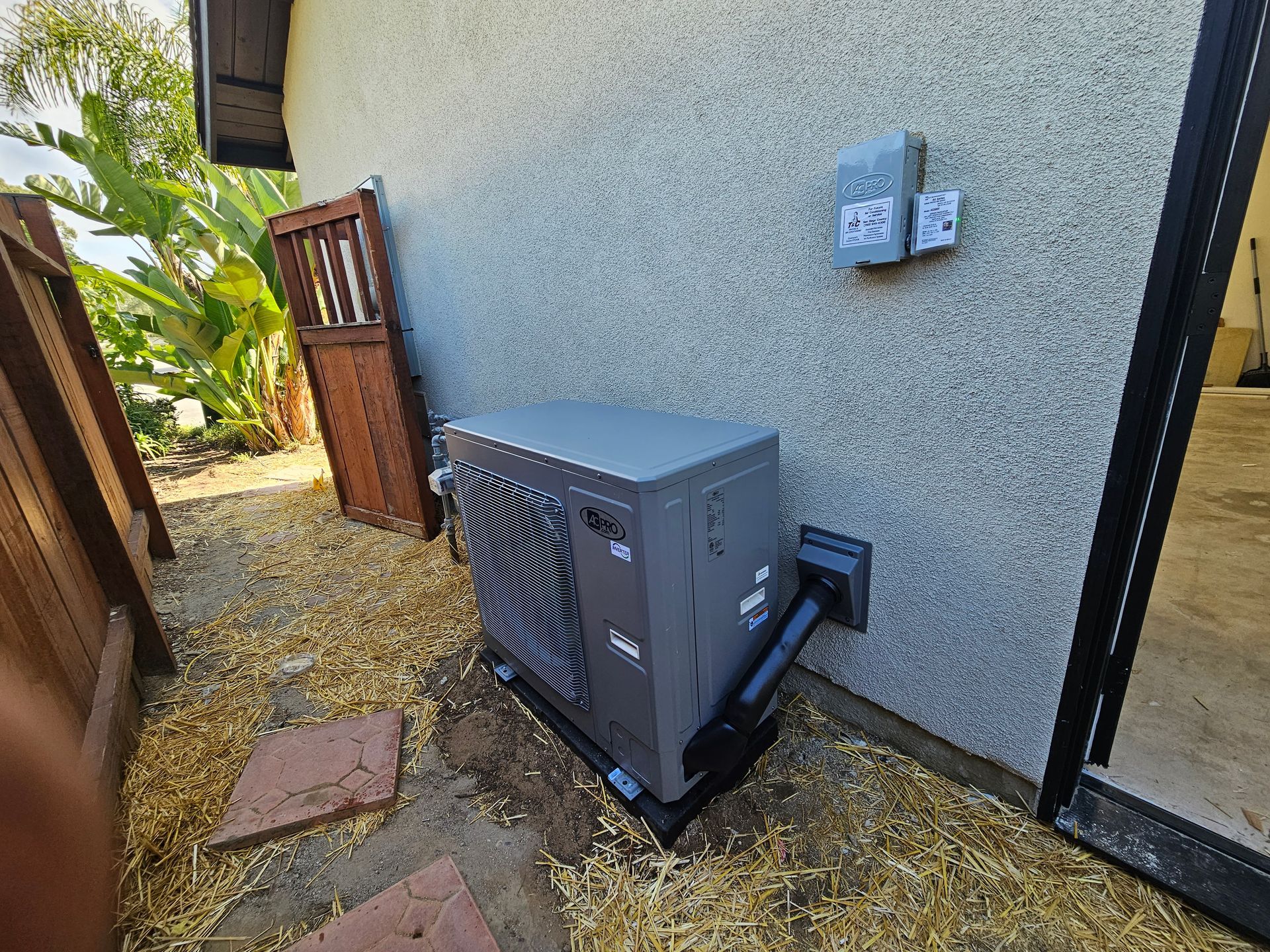 Pool heater mounted on a wall next to a sliding door. Brown fence and door in the background.