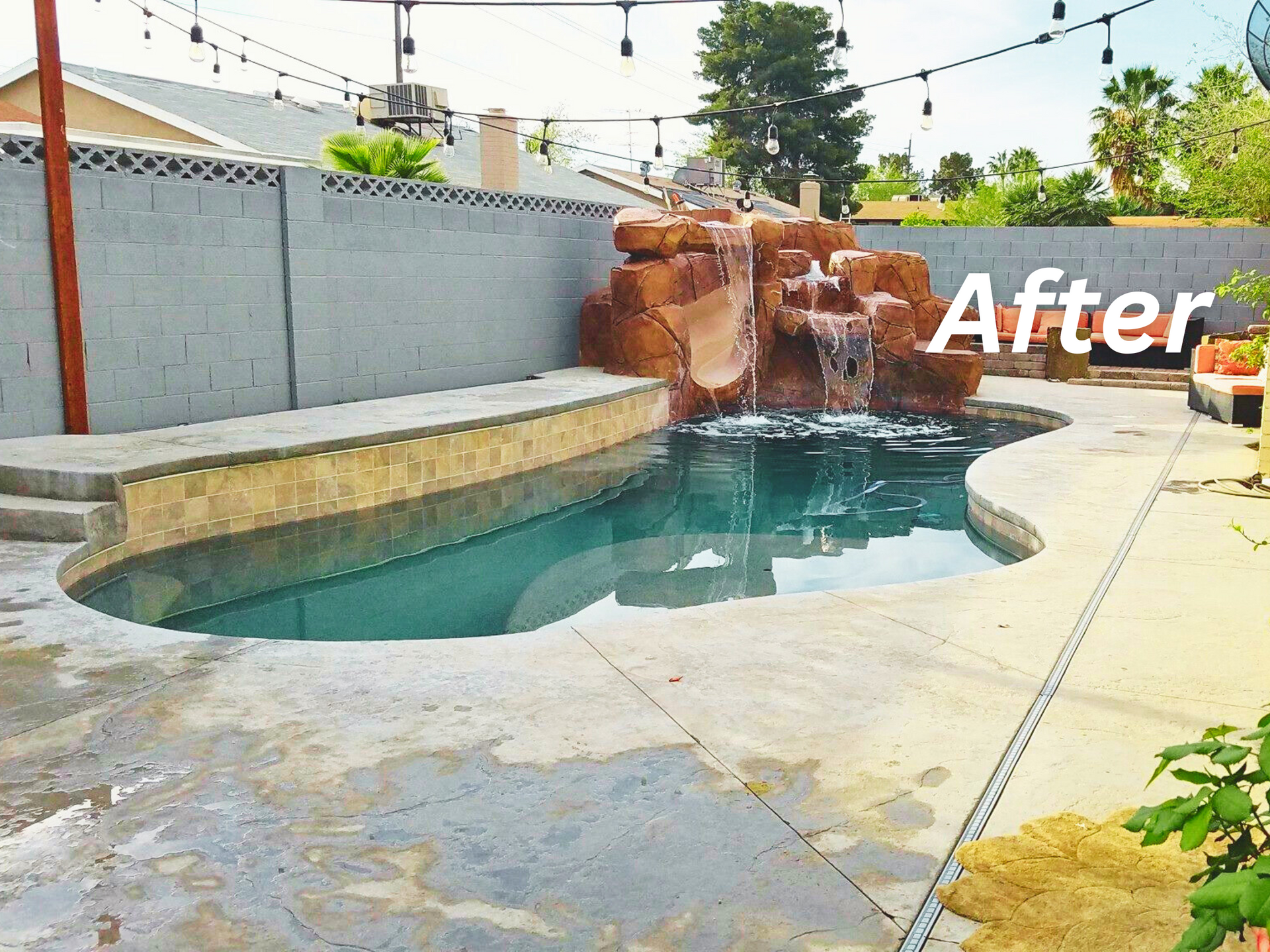 Backyard pool with waterfall feature and concrete patio, after renovation.