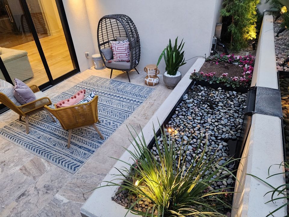 Lit-up house at night, with a tree and low-lying lights illuminating the yard and facade. A car is parked in the driveway.
