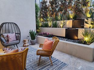 Patio with tiered fountain, lounge chairs, plants, and accent lighting.