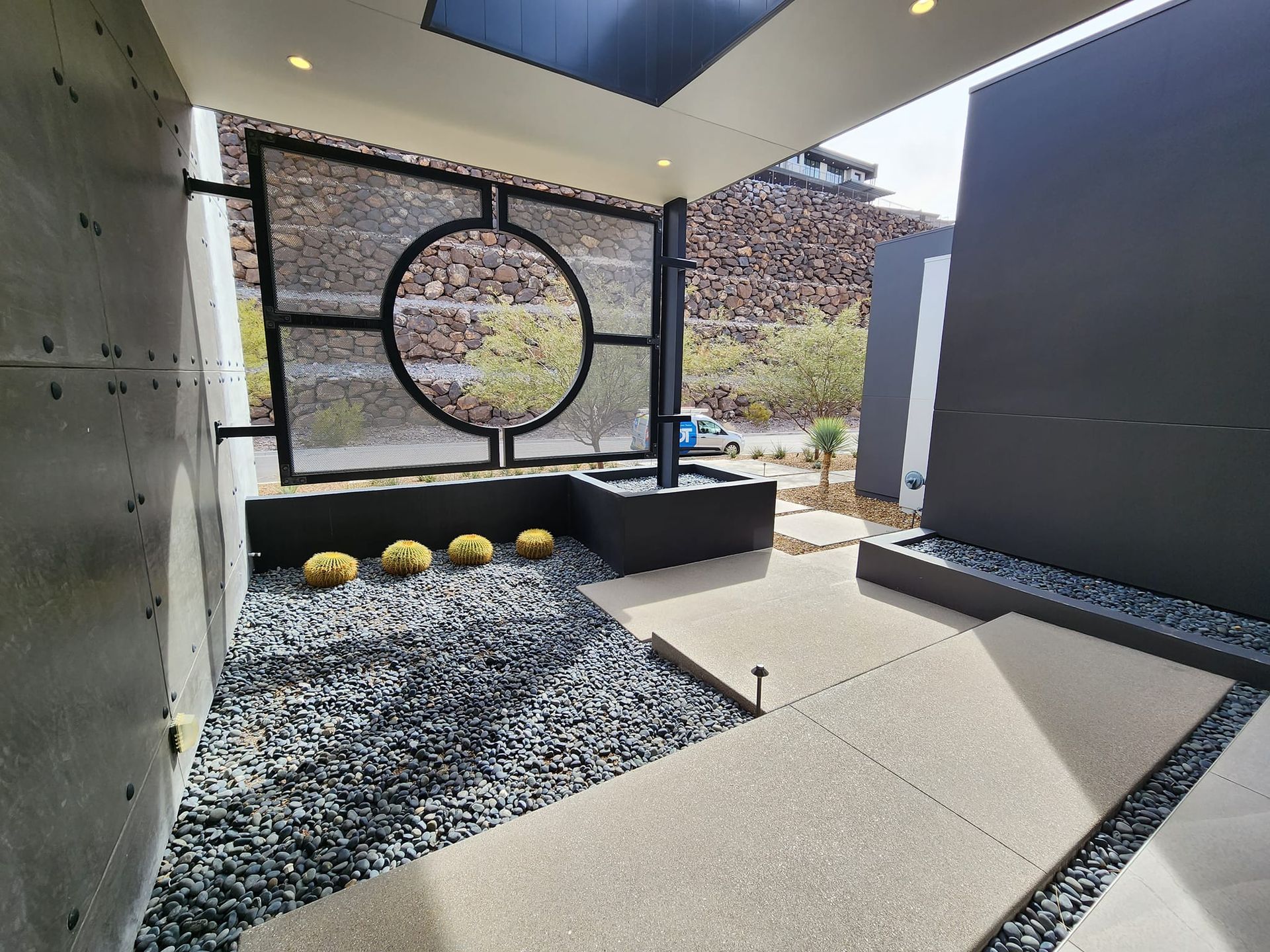 Zen garden patio with black metal screen, water feature, gravel, and minimalist design.