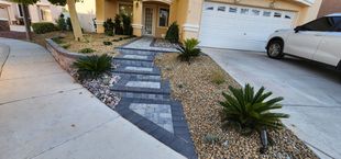 Front yard with stone steps leading to a house entrance; gravel and plants surround the steps.