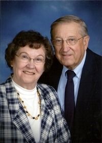 A smiling couple posing for a portrait against a blue studio background.