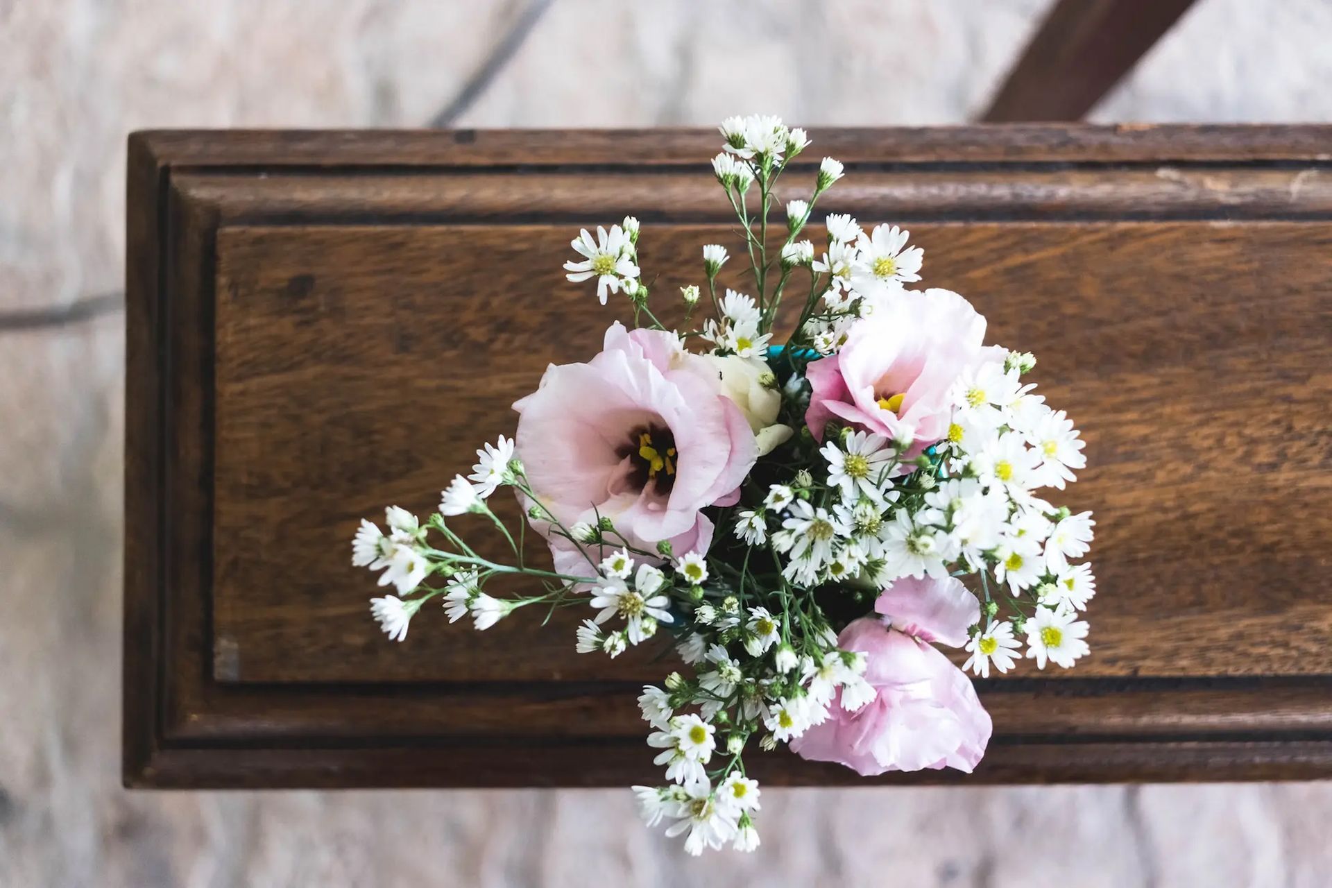 Floral bouquet of pink and white flowers on a dark wooden plaque