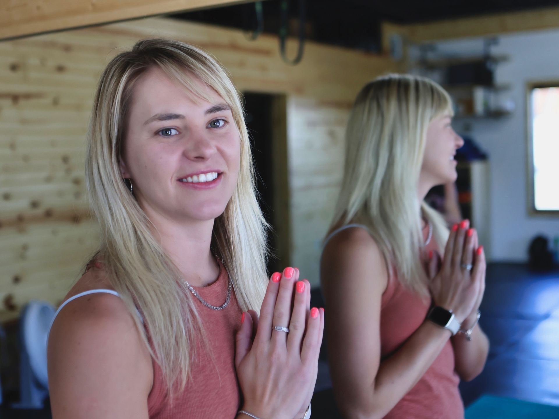 A woman is standing in front of a mirror with her hands folded in prayer