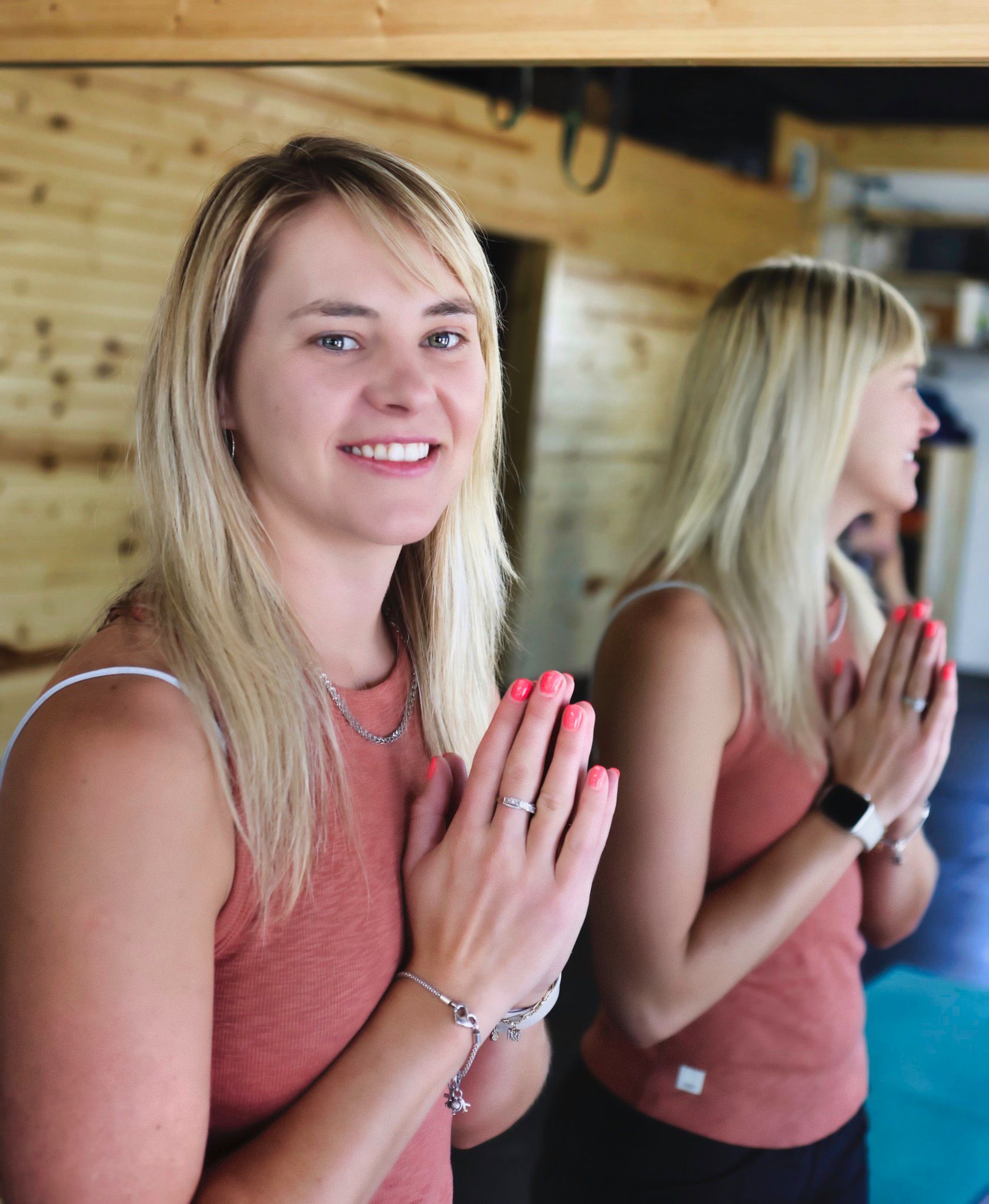 A woman is standing in front of a mirror with her hands folded in prayer.