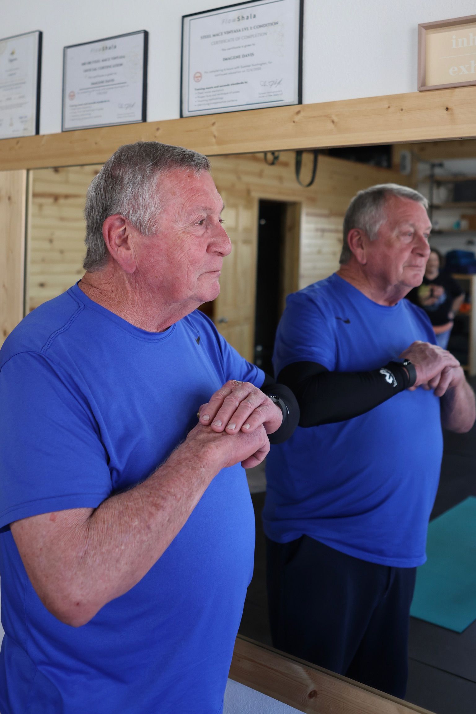 A man in a blue shirt is looking at his reflection in a mirror.