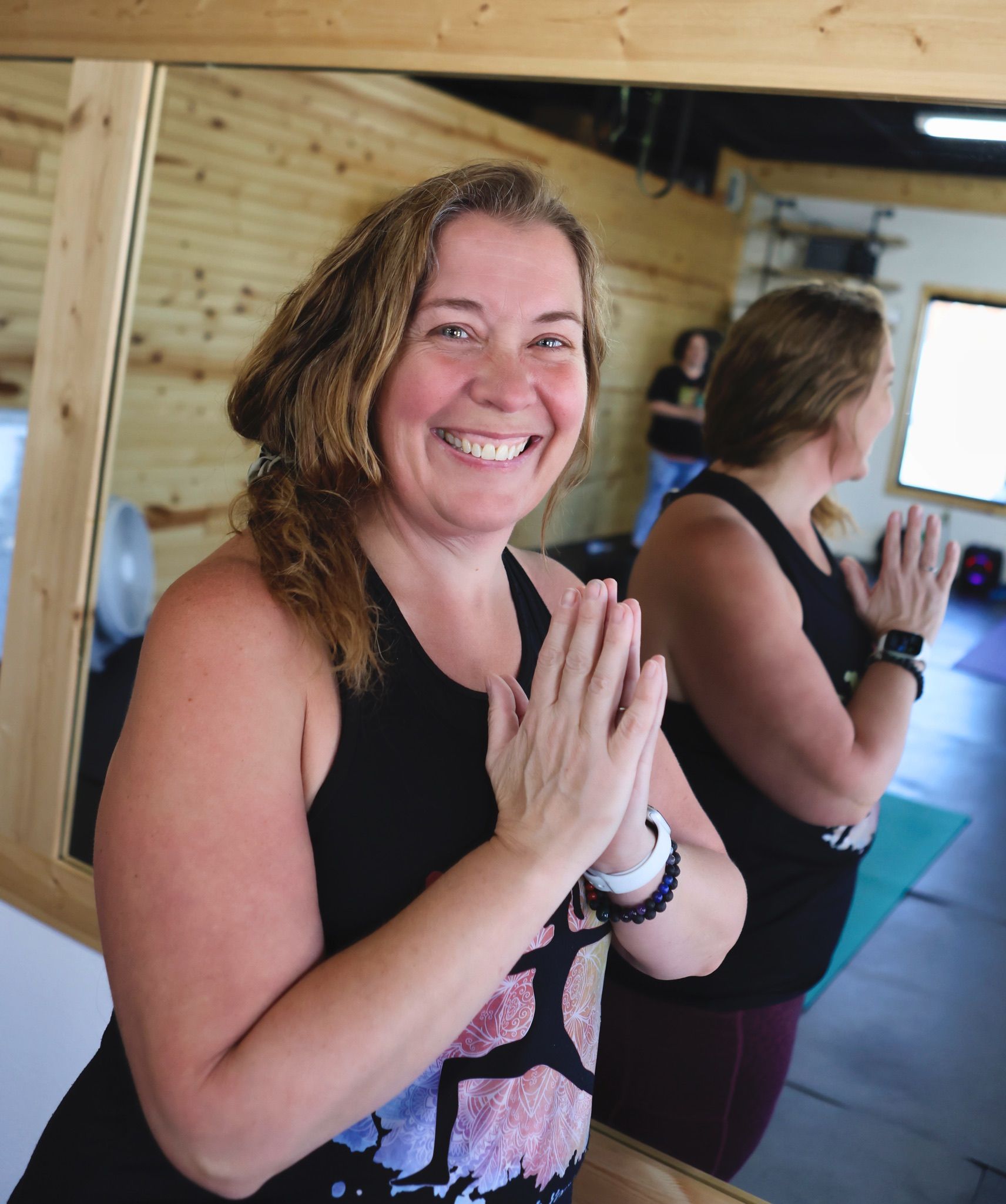 A woman is smiling while standing in front of a mirror