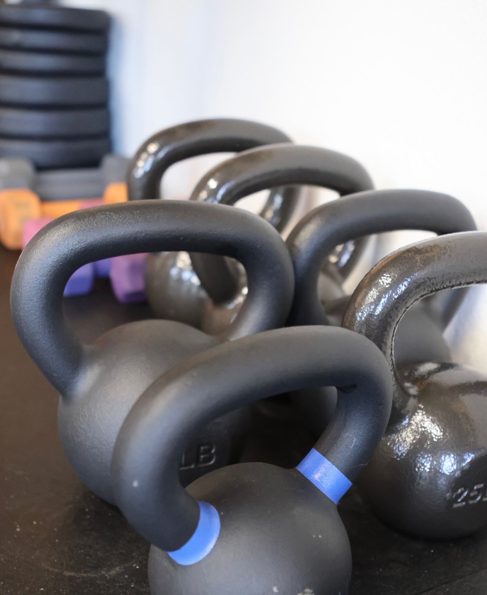 A row of black kettlebells with blue handles