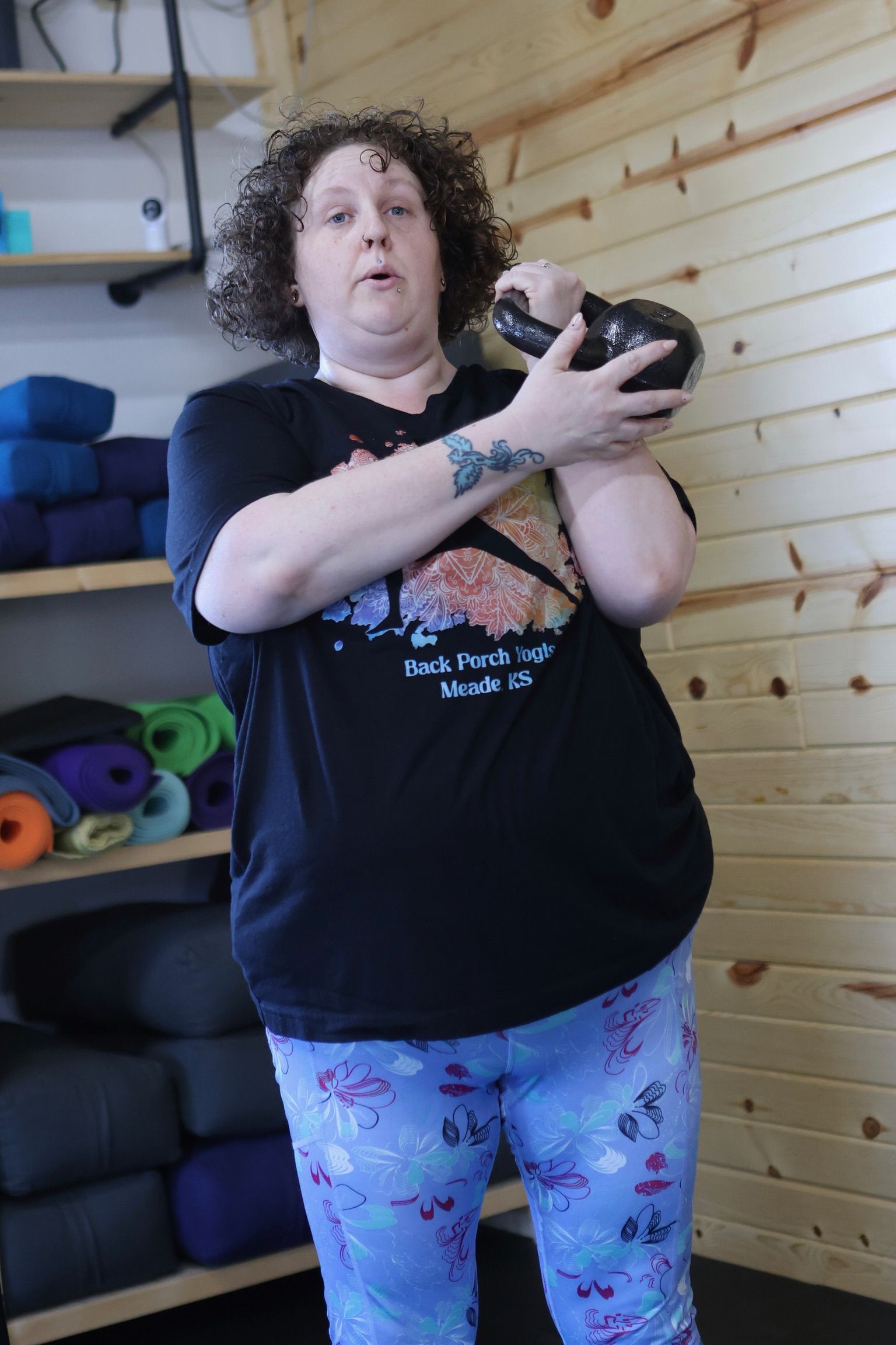 A woman is standing in a room holding a kettlebell.