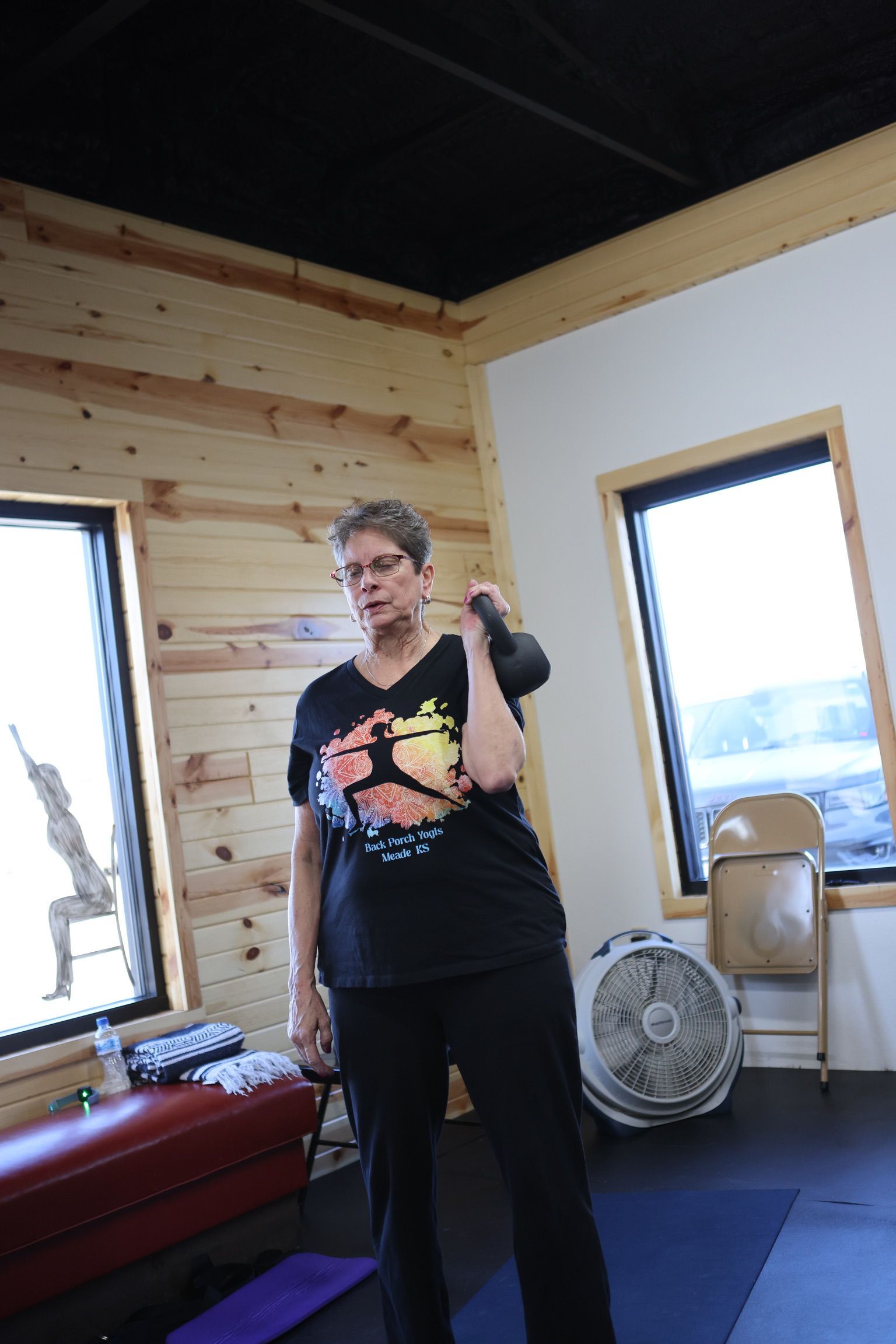 A woman is standing in a room holding a kettlebell.