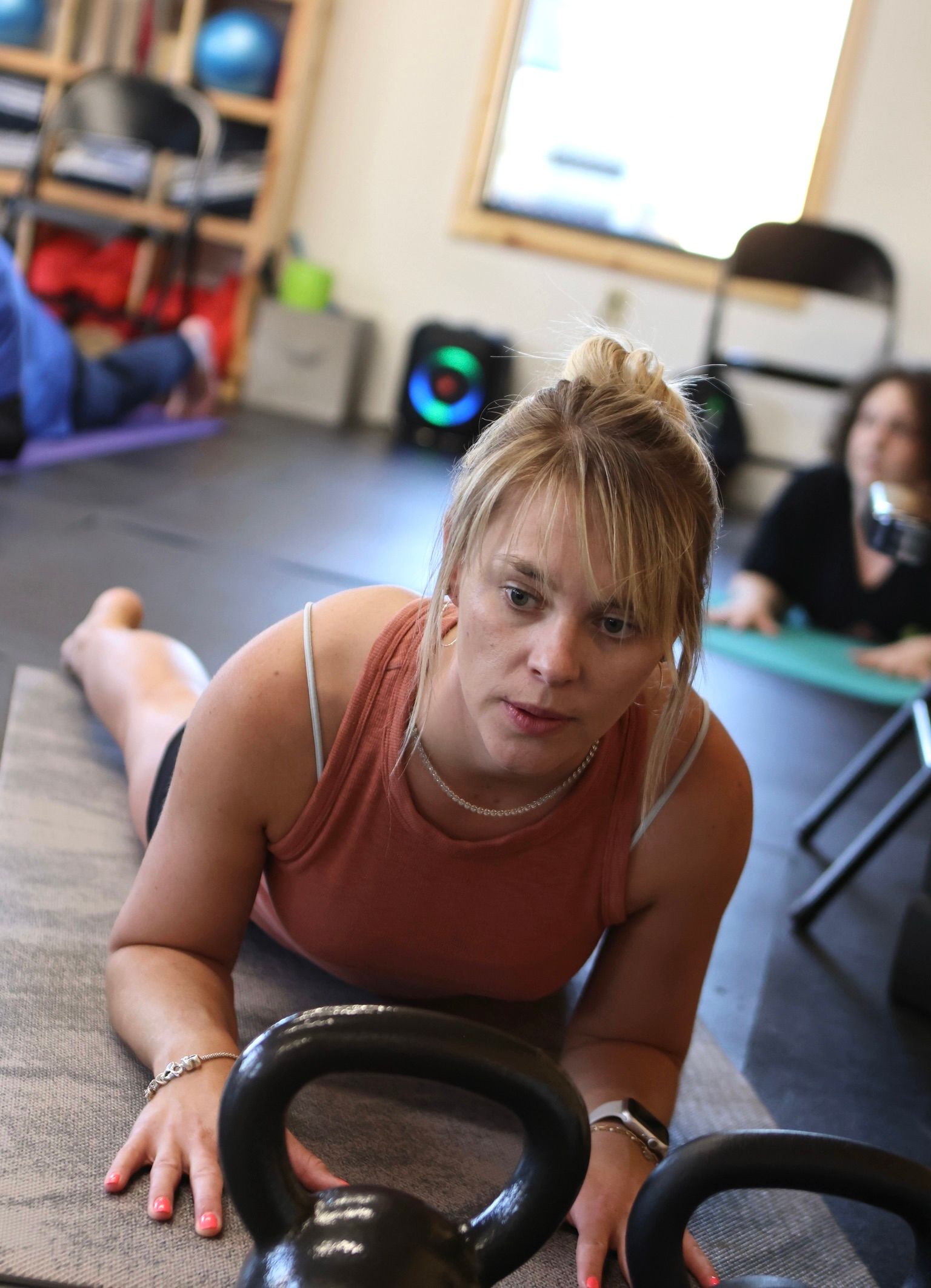 A woman is laying on the floor holding a kettlebell