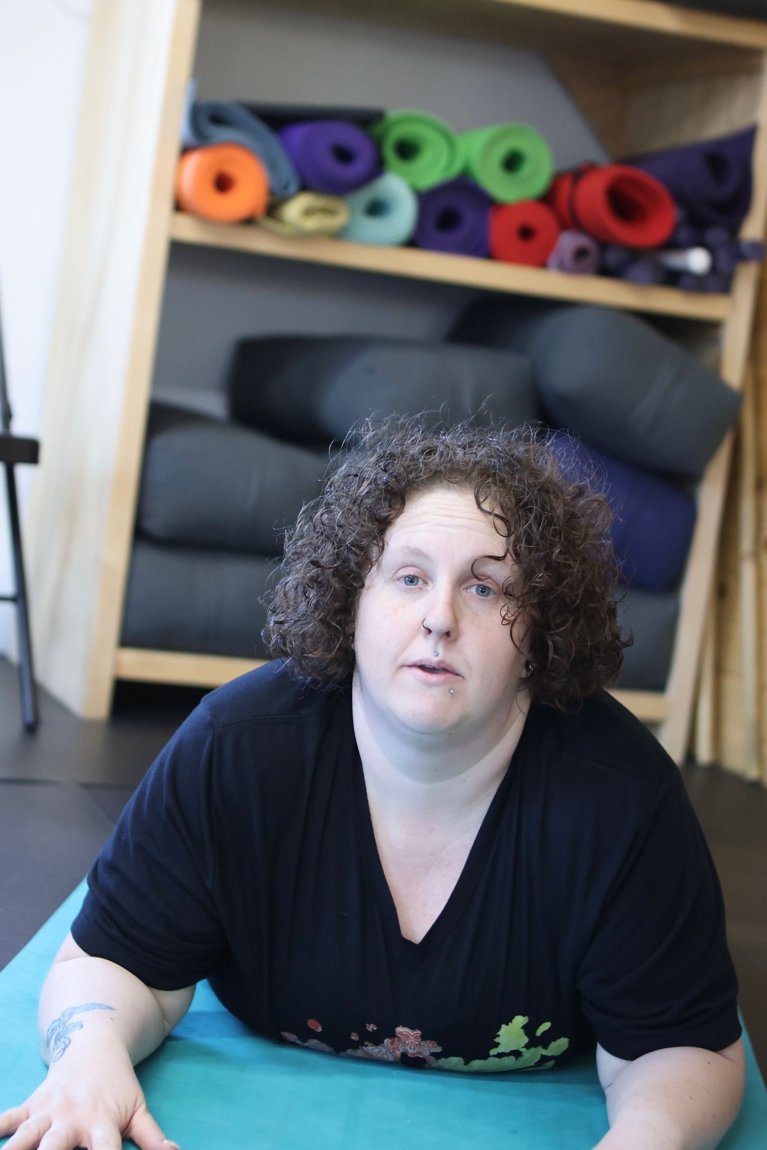 A woman with curly hair is laying on a yoga mat