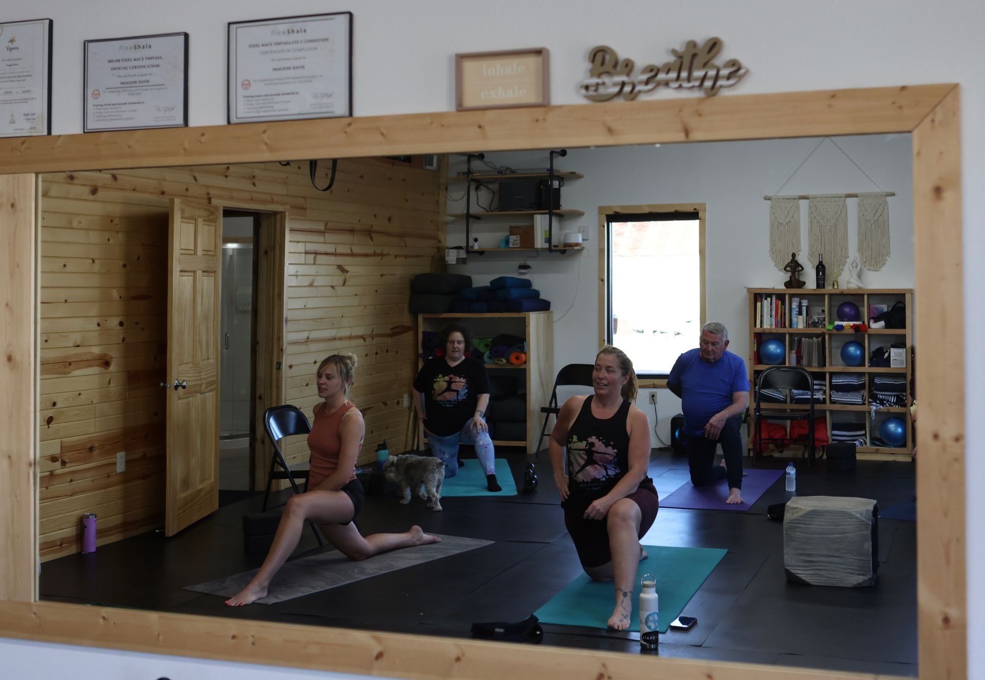 A group of people are doing yoga in front of a large mirror
