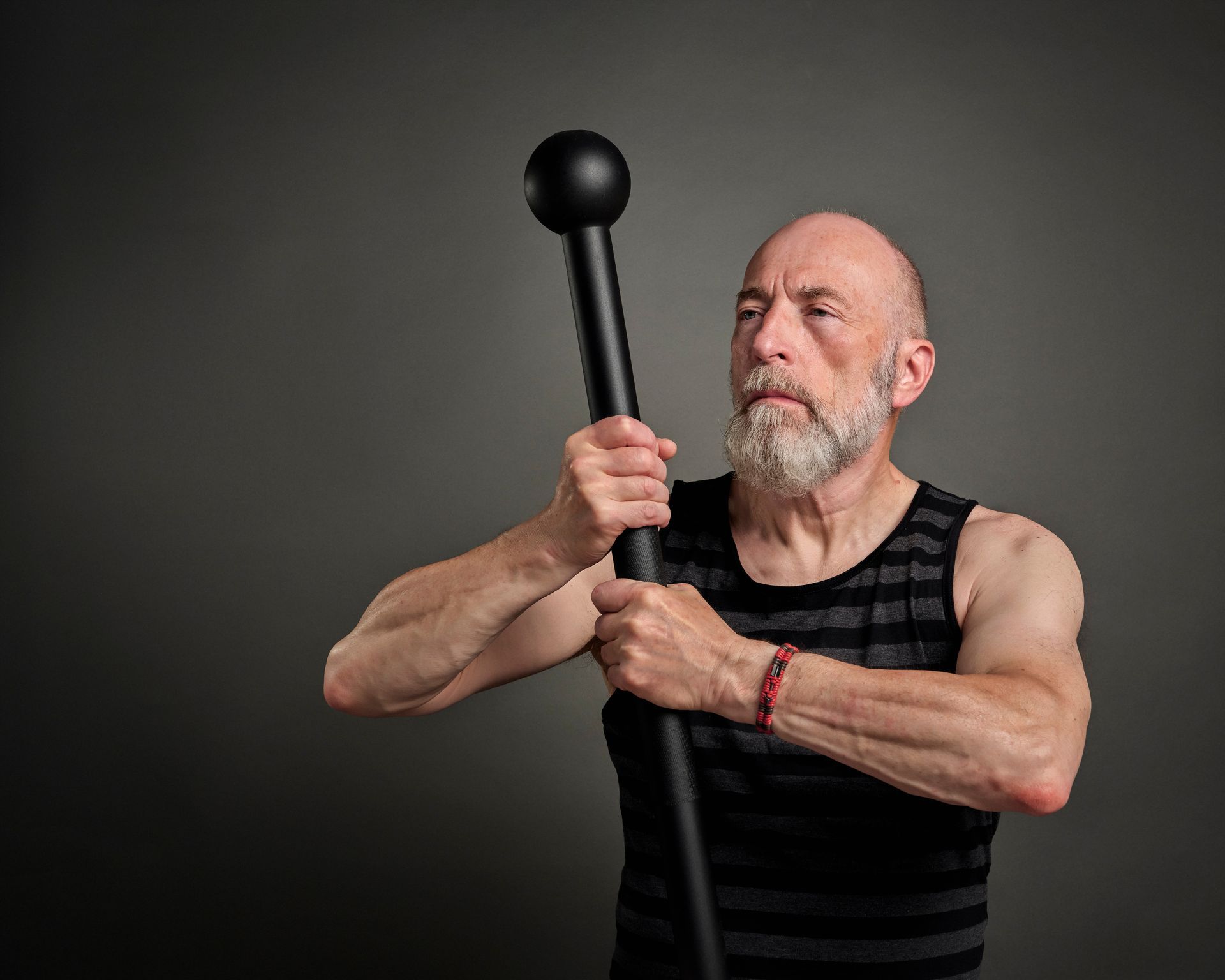 A bald man with a beard is holding a pole with a ball on it.