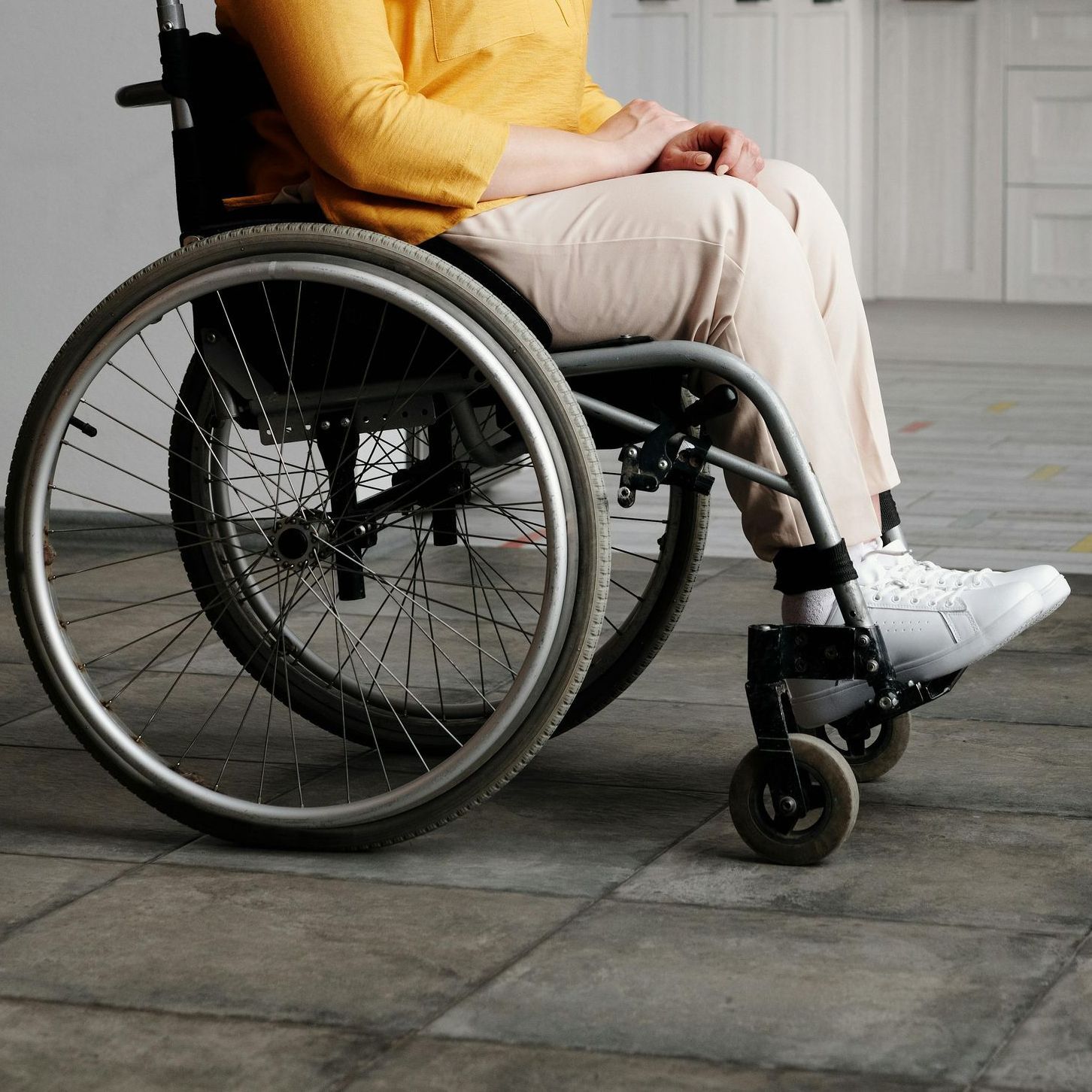A woman in a yellow shirt is sitting in a wheelchair