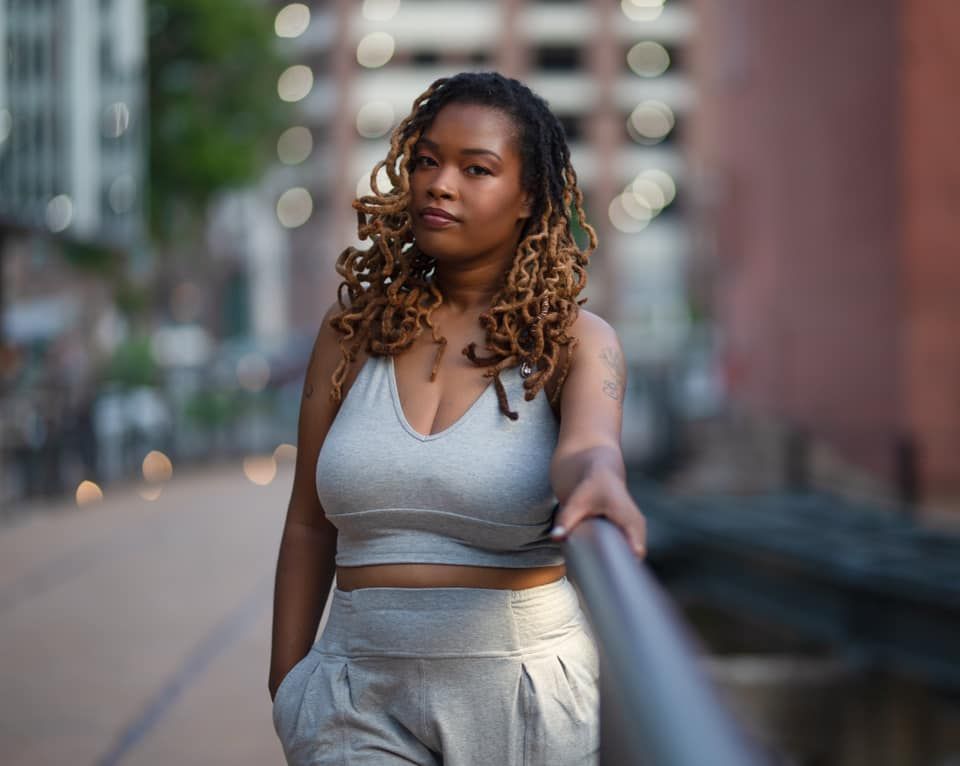 A woman in a crop top and shorts is standing next to a railing.