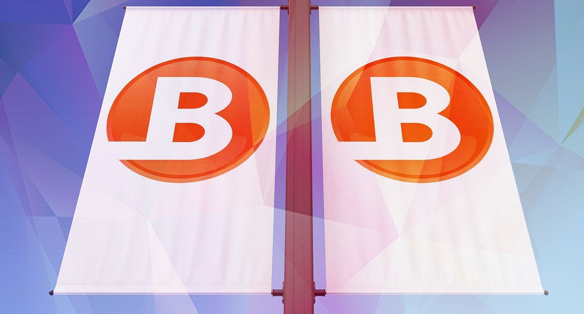 Two flags with the letter b on them are hanging on a pole.