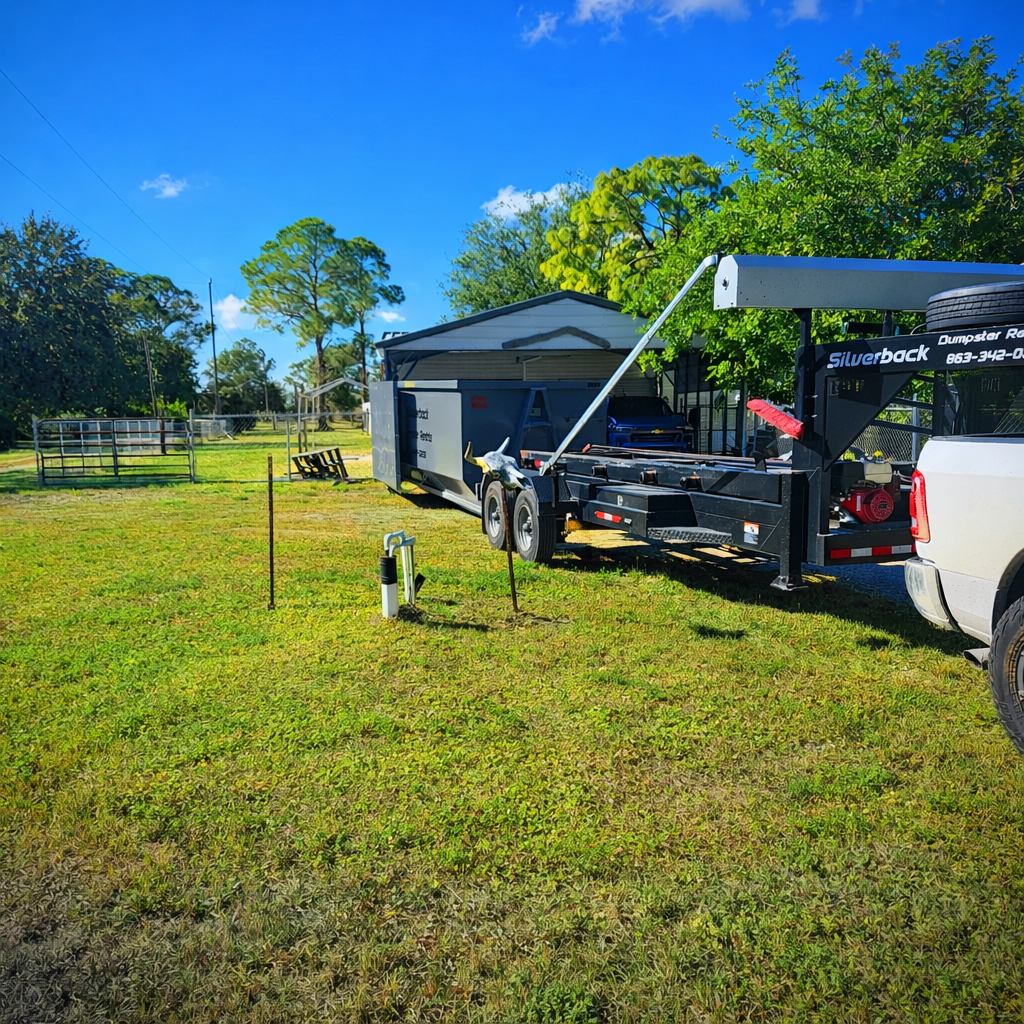 Brown dumpster in a parking lot, near green container, trees in the background.