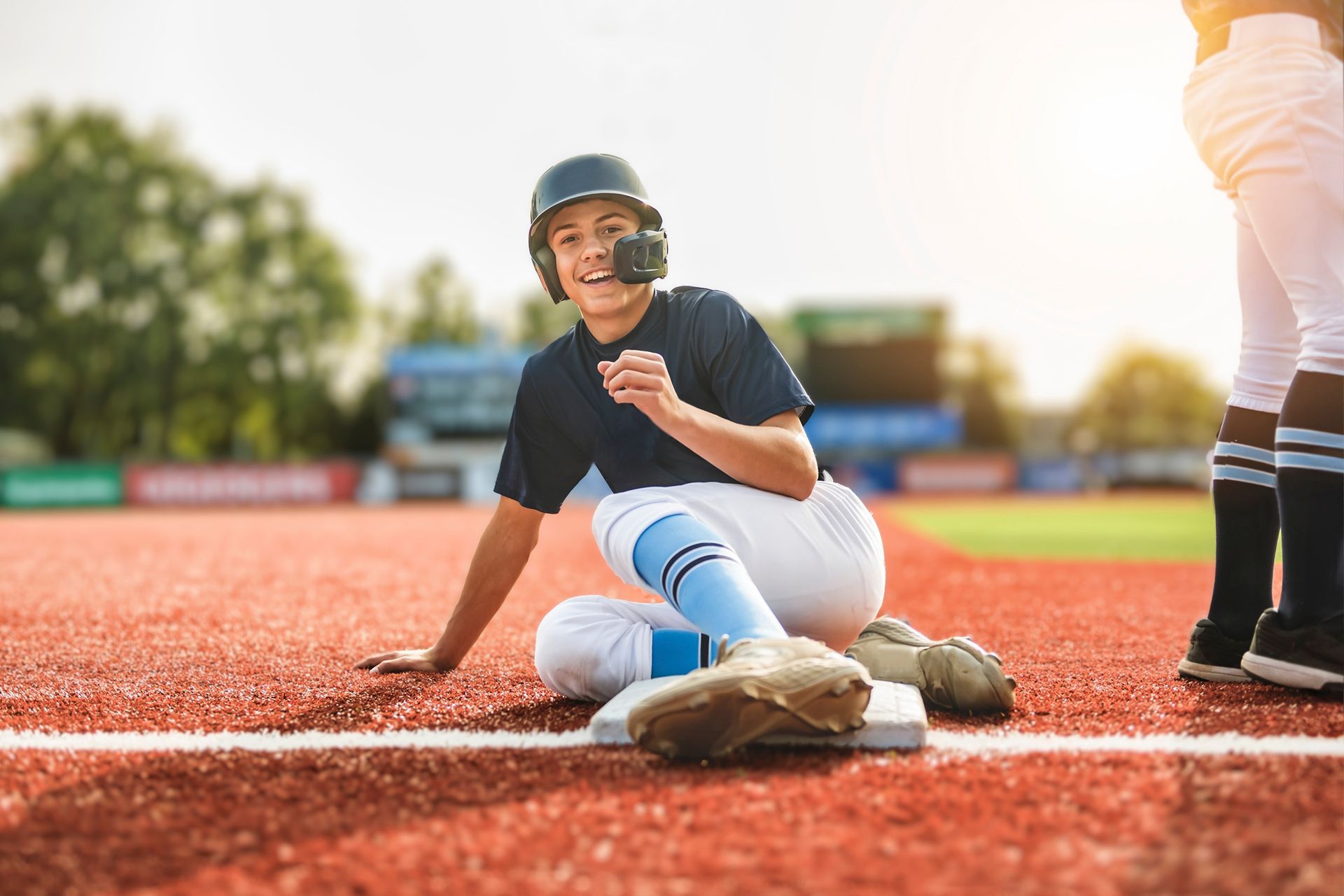 Baseball player sliding into base, smiling.
