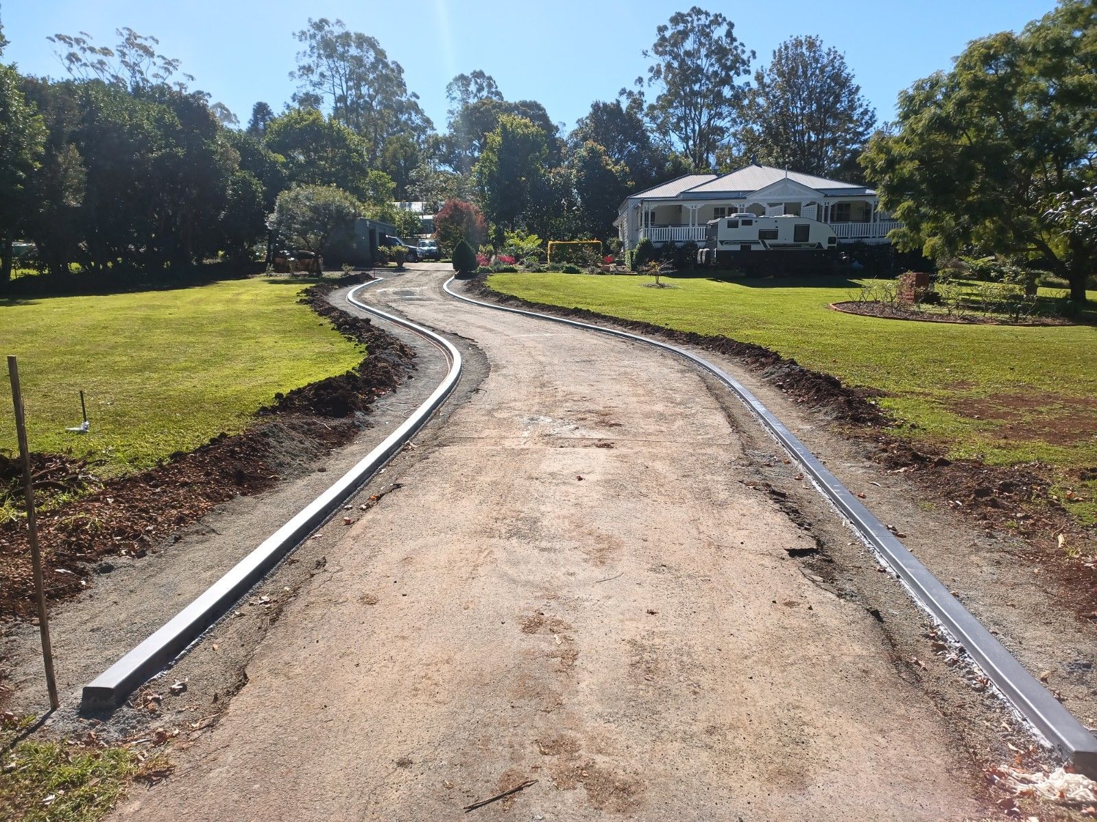 A dirt road with a white house in the background