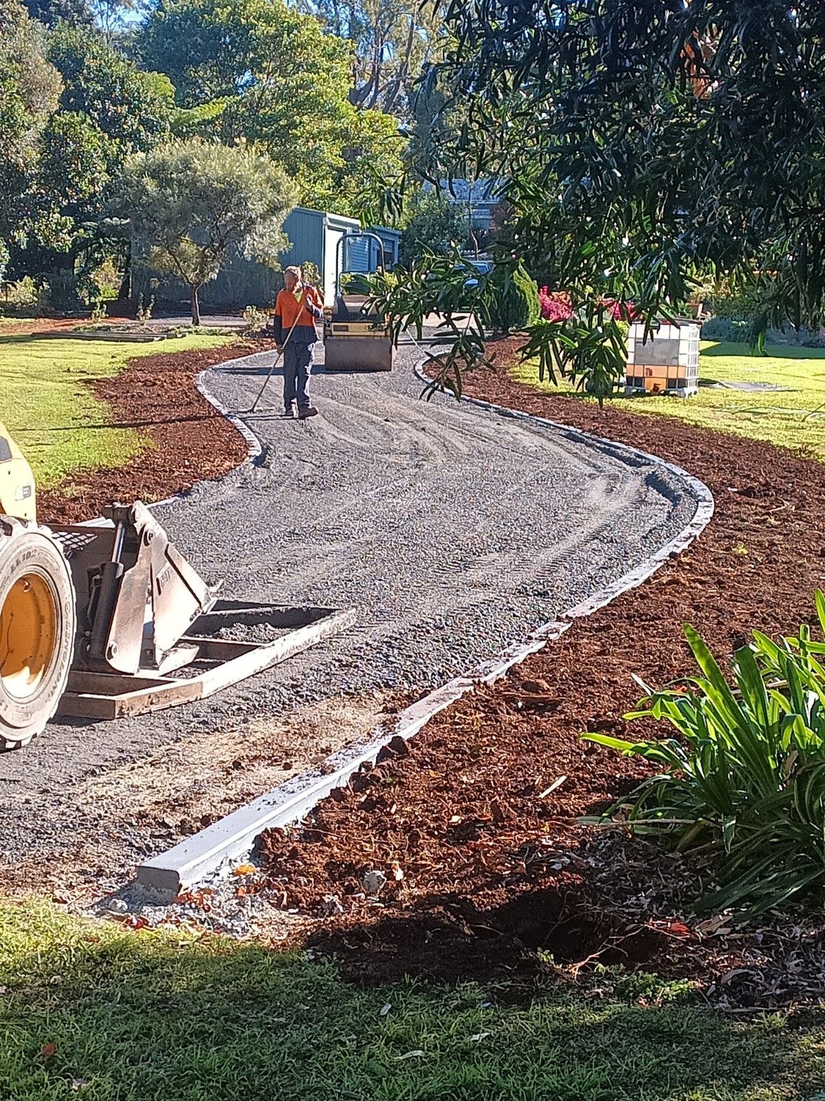 A man is walking down a gravel path next to a bulldozer.