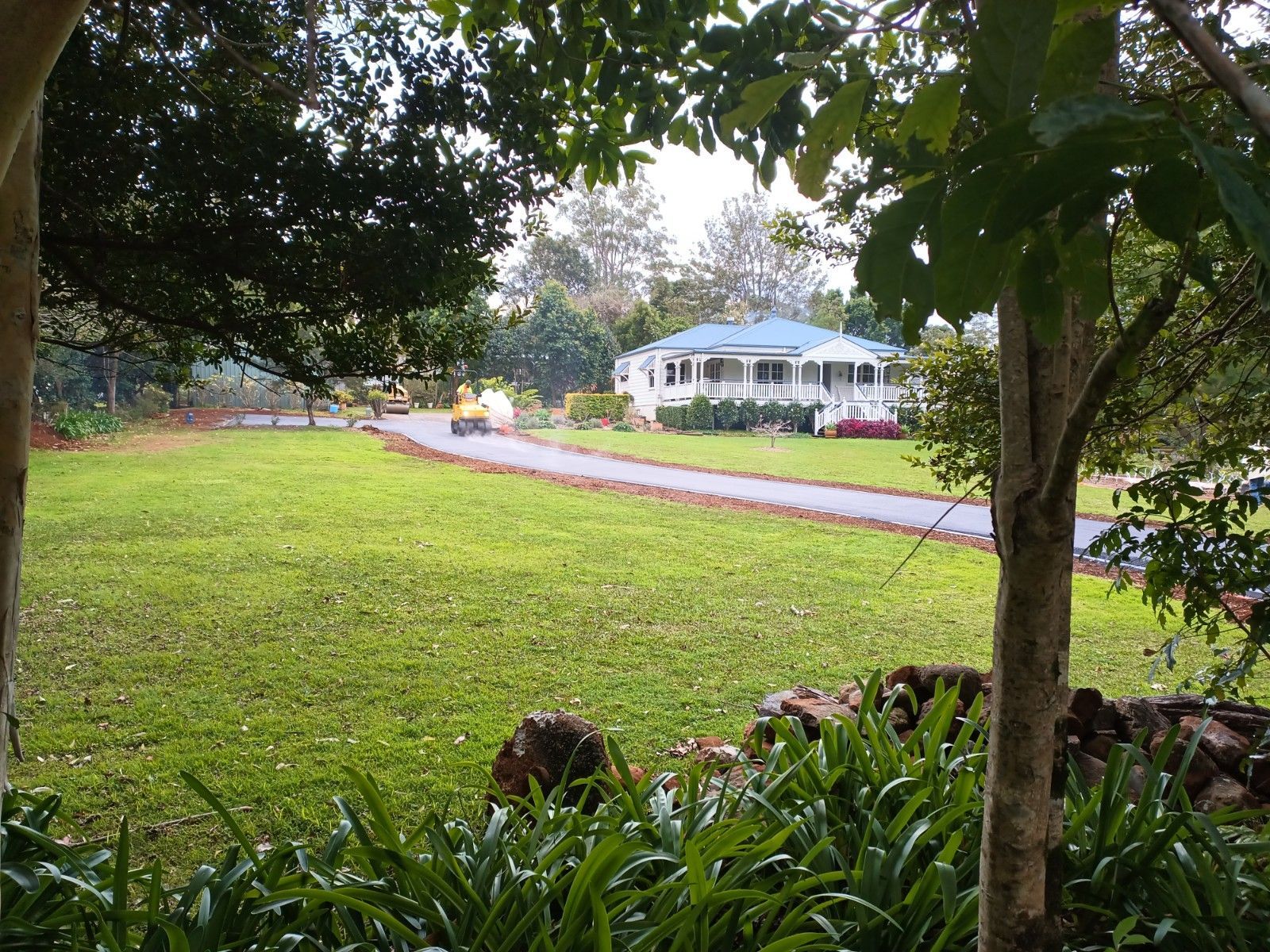 A house with a blue roof sits in the middle of a lush green field