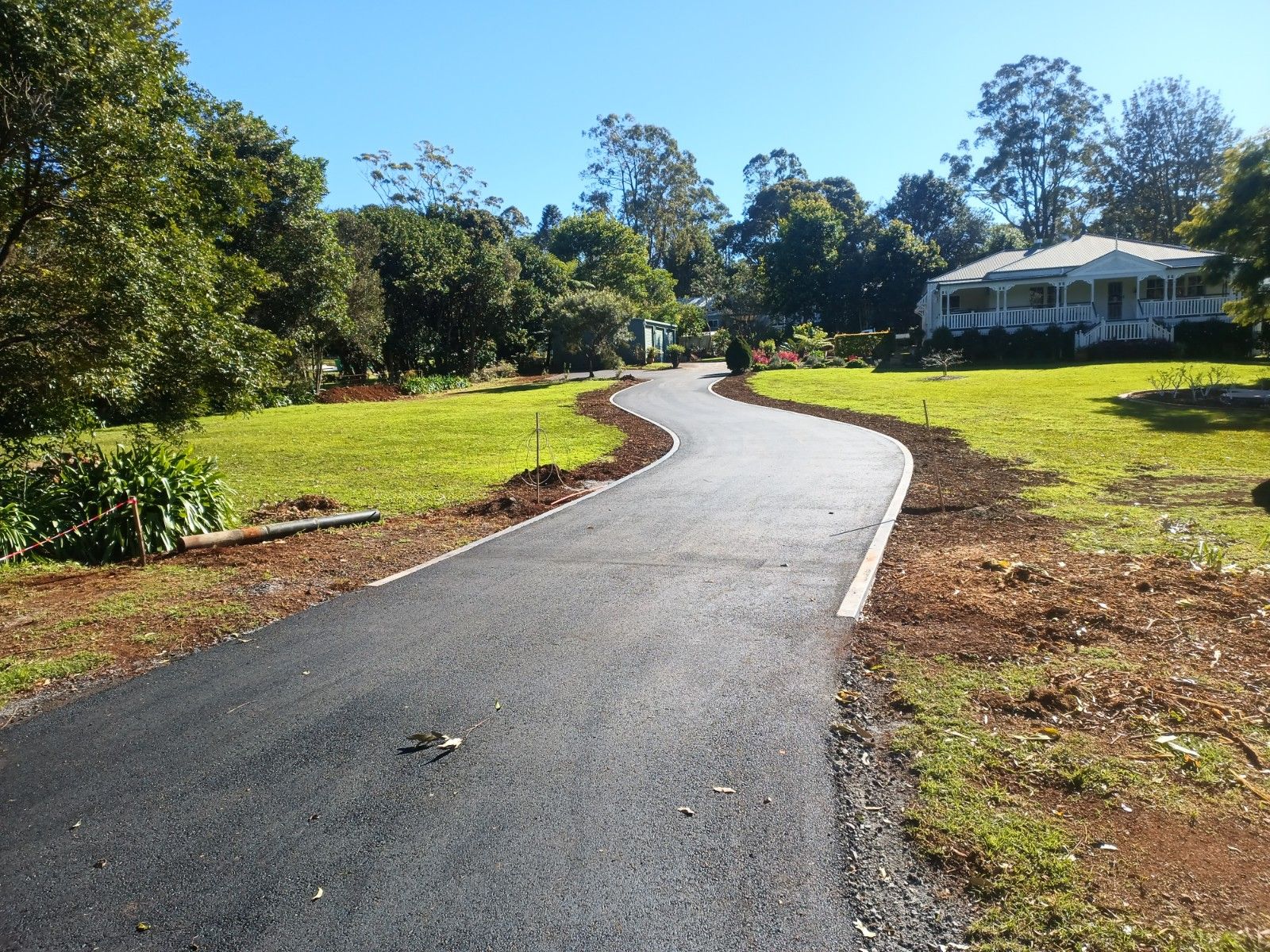A road going through a grassy field with a house in the background