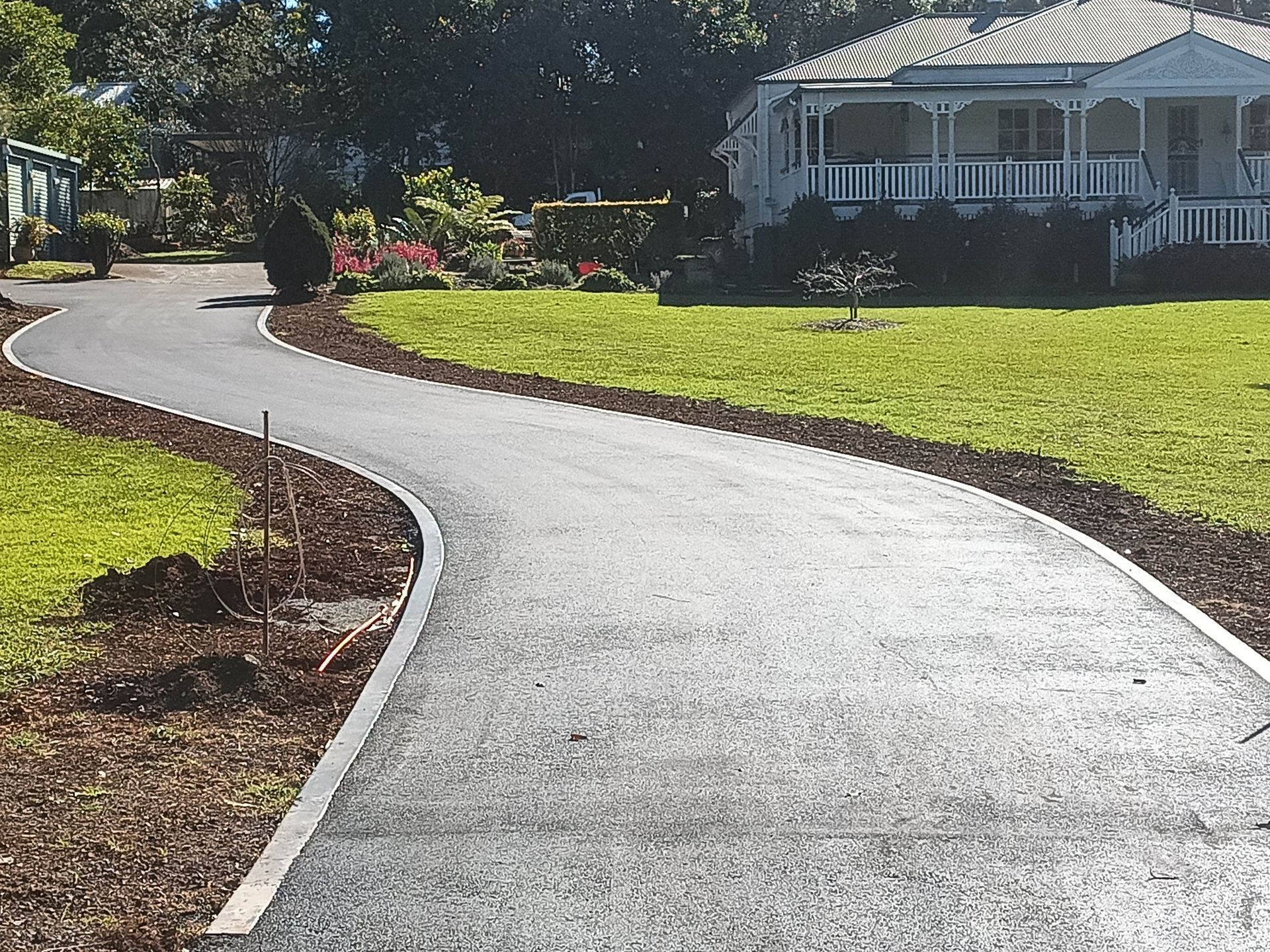 A driveway leading to a white house with a porch